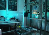 Zdjęcie przedstawia urządzenie do anenometrii dopplerowskiej (w środku zdjęcia), które znajduje się w laboratorium i jest ustawione do badania prędkości przepływu cieczy w przezroczystym zbiorniku.
